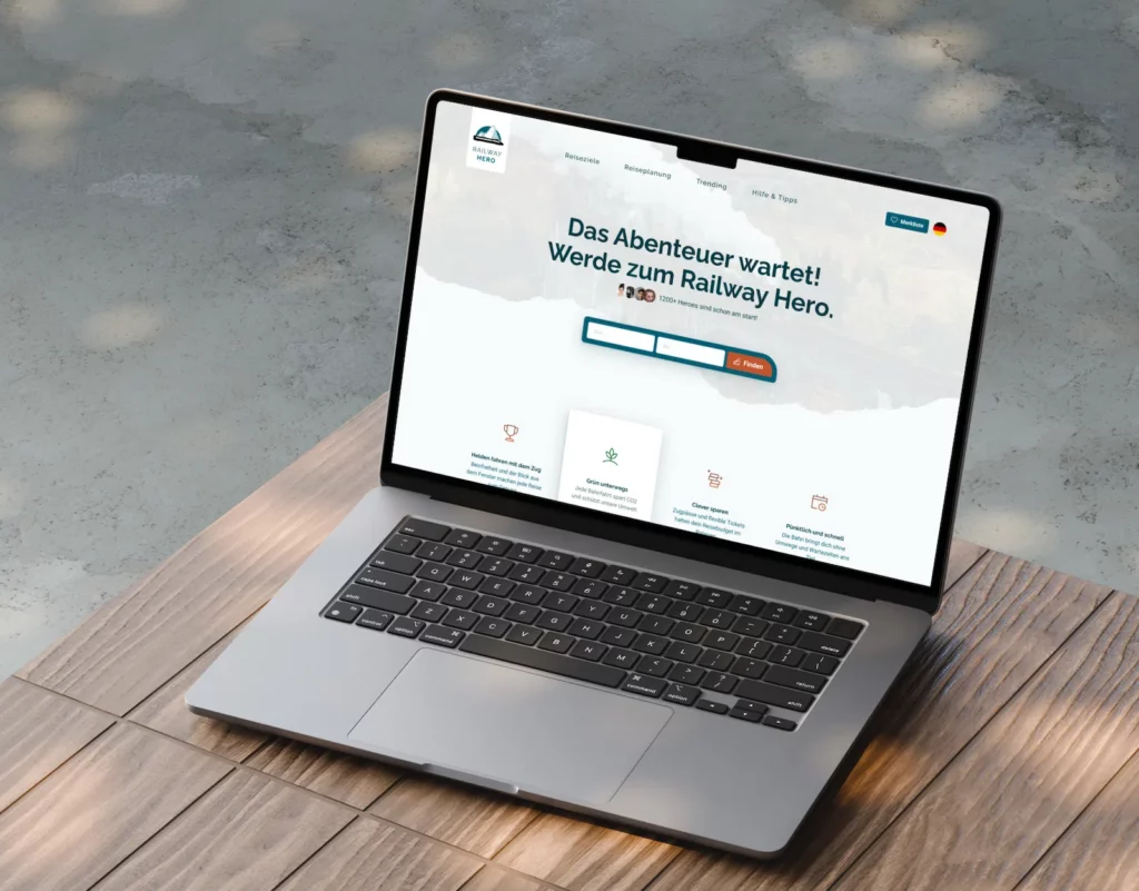 A laptop displaying the Railway Hero website design with a focus on corporate design elements. The screen shows the homepage in German, featuring navigation tabs and a search function. The title reads "Das Abenteuer wartet! Werde zum Railway Hero." The background is a light, natural setting with soft shadows on a wooden surface.